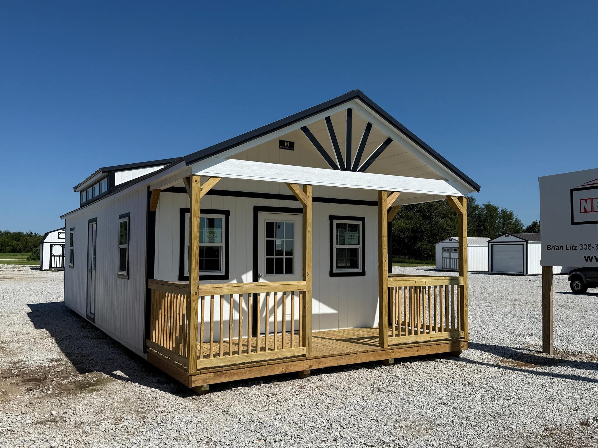 Exterior view of a large white cabin with a lumber front porch.