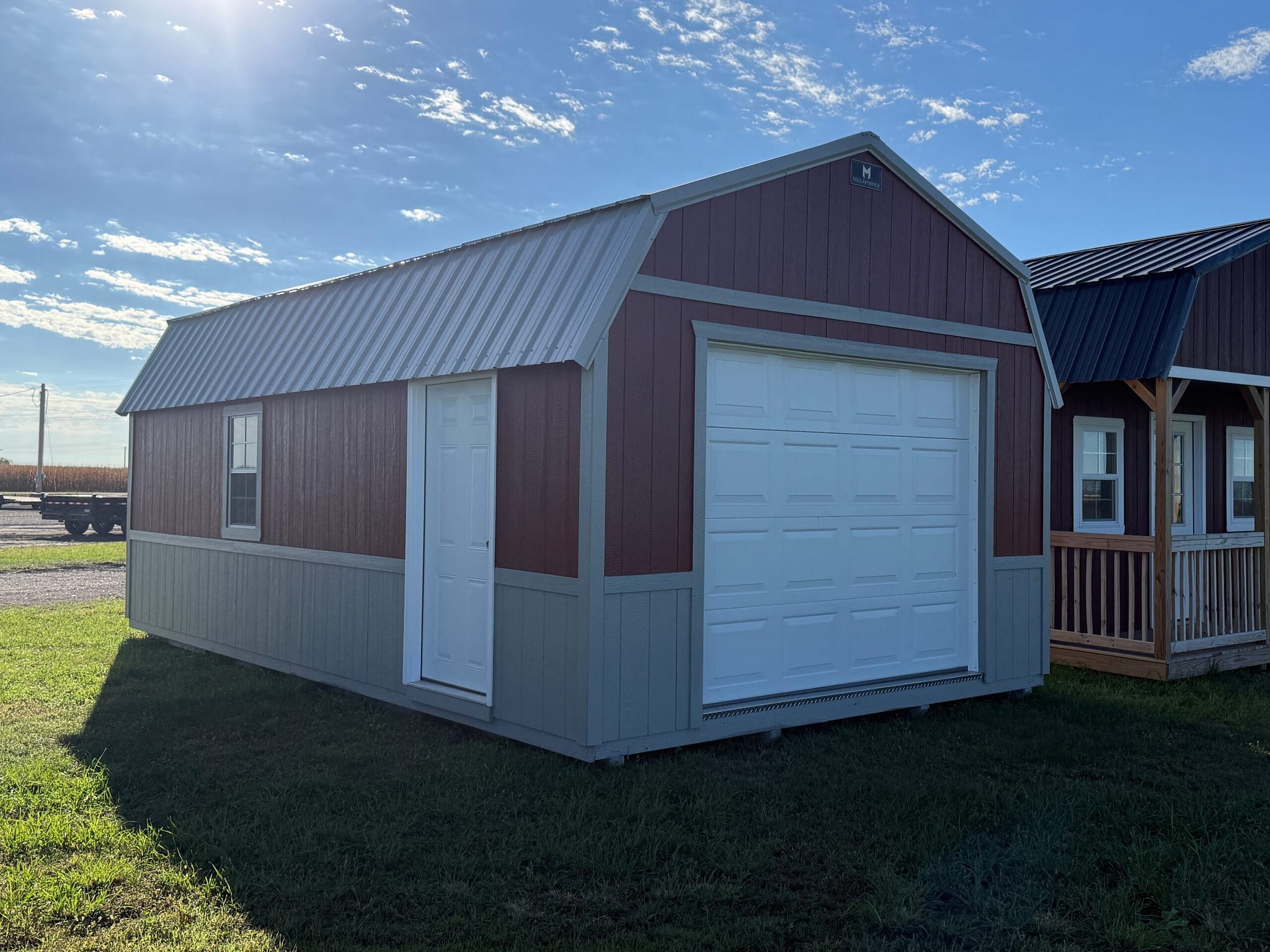 Exterior of large, almost barn-style garage showcasing a car garage door with a side door.