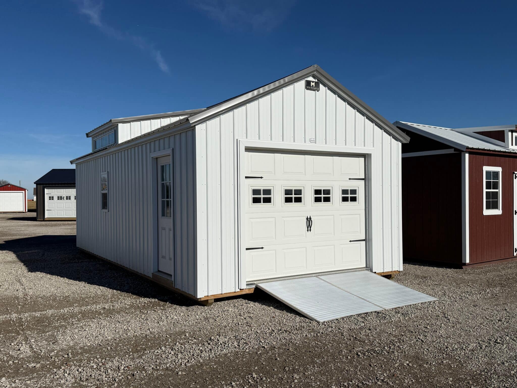 A large, detached garage showcasing the garage door, dormer on top, and side access door.
