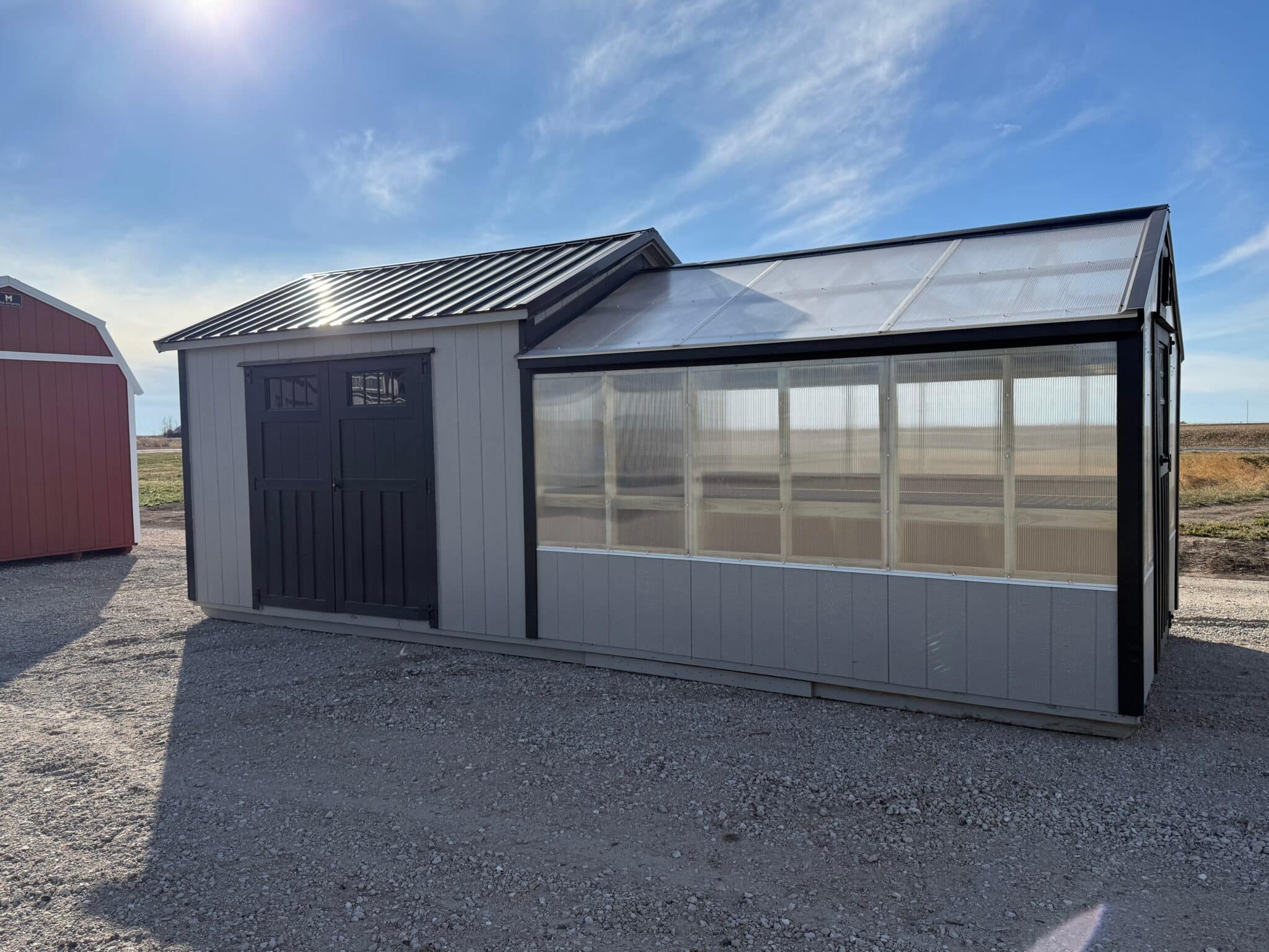 Grey greenhouse with attached storage shed.