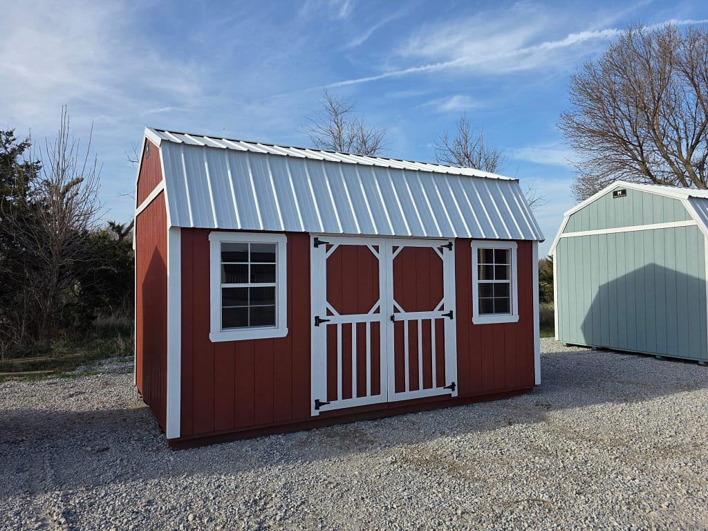 Exterior of a wide shed with double doors and two windows in the front.