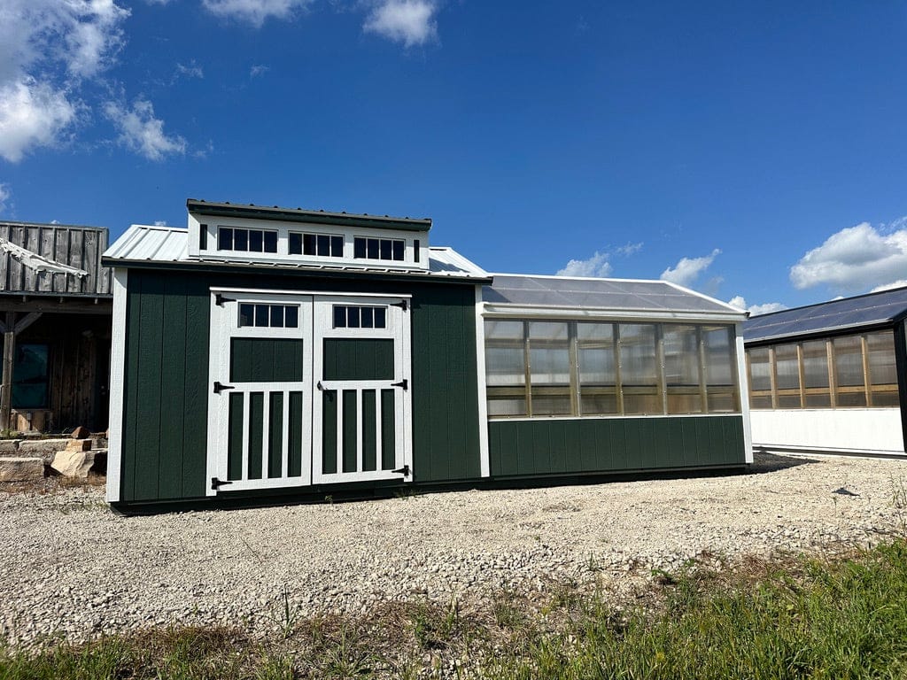 Exterior of green and white greenhouse with shed attached.