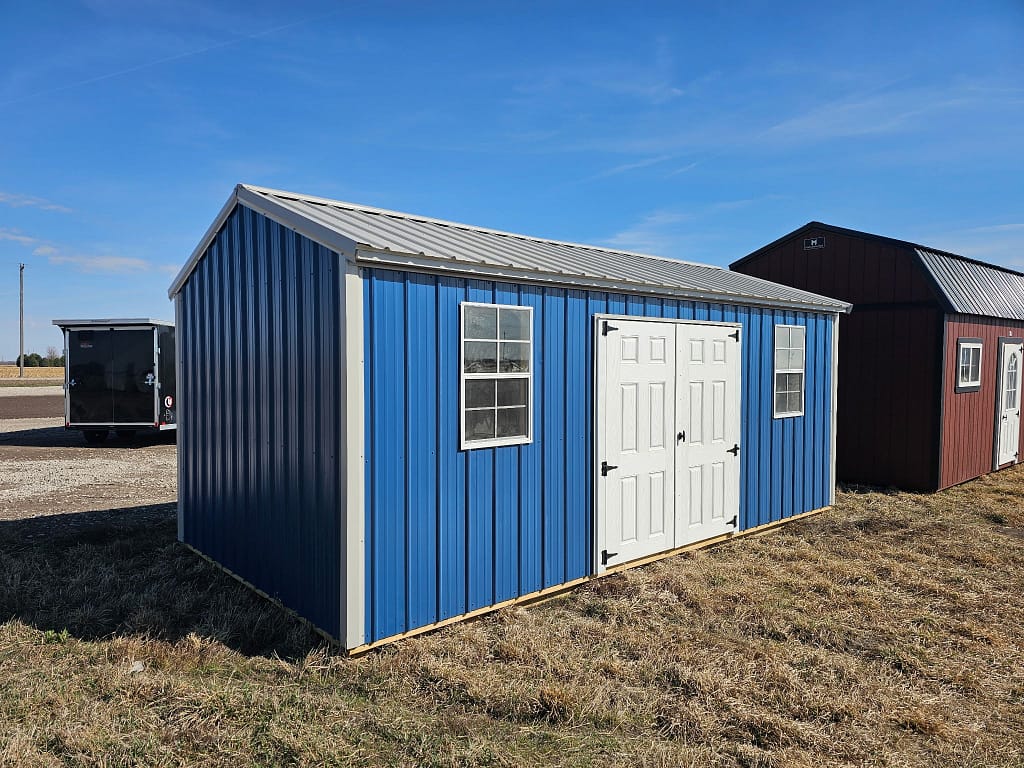 Exterior view of a long shed with a set of double doors and two windows.