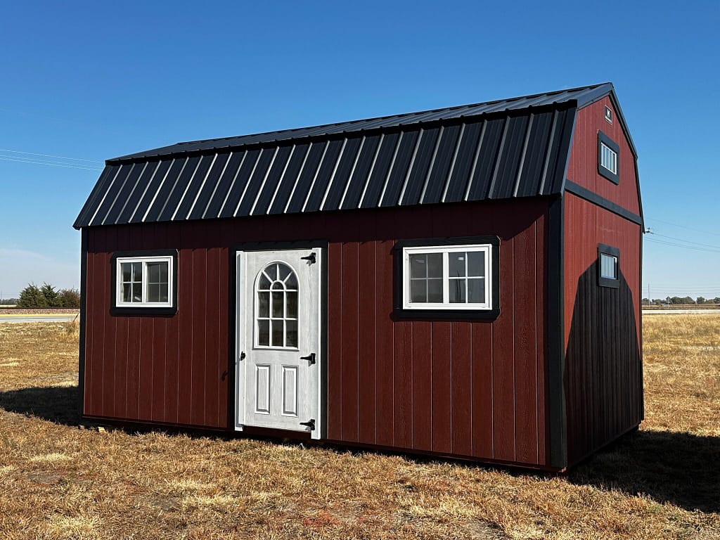 Exterior of large shed, showcasing a door and two windows with white trim.