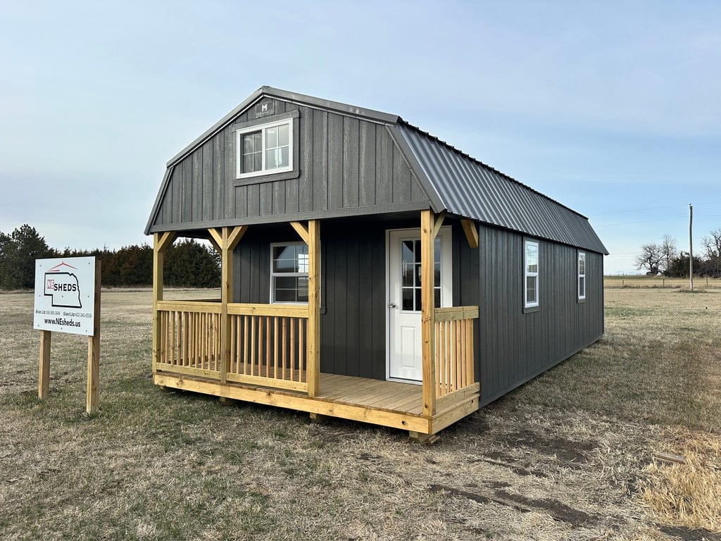 Exterior of a long cabin or ADU with a wood porch and loft window.