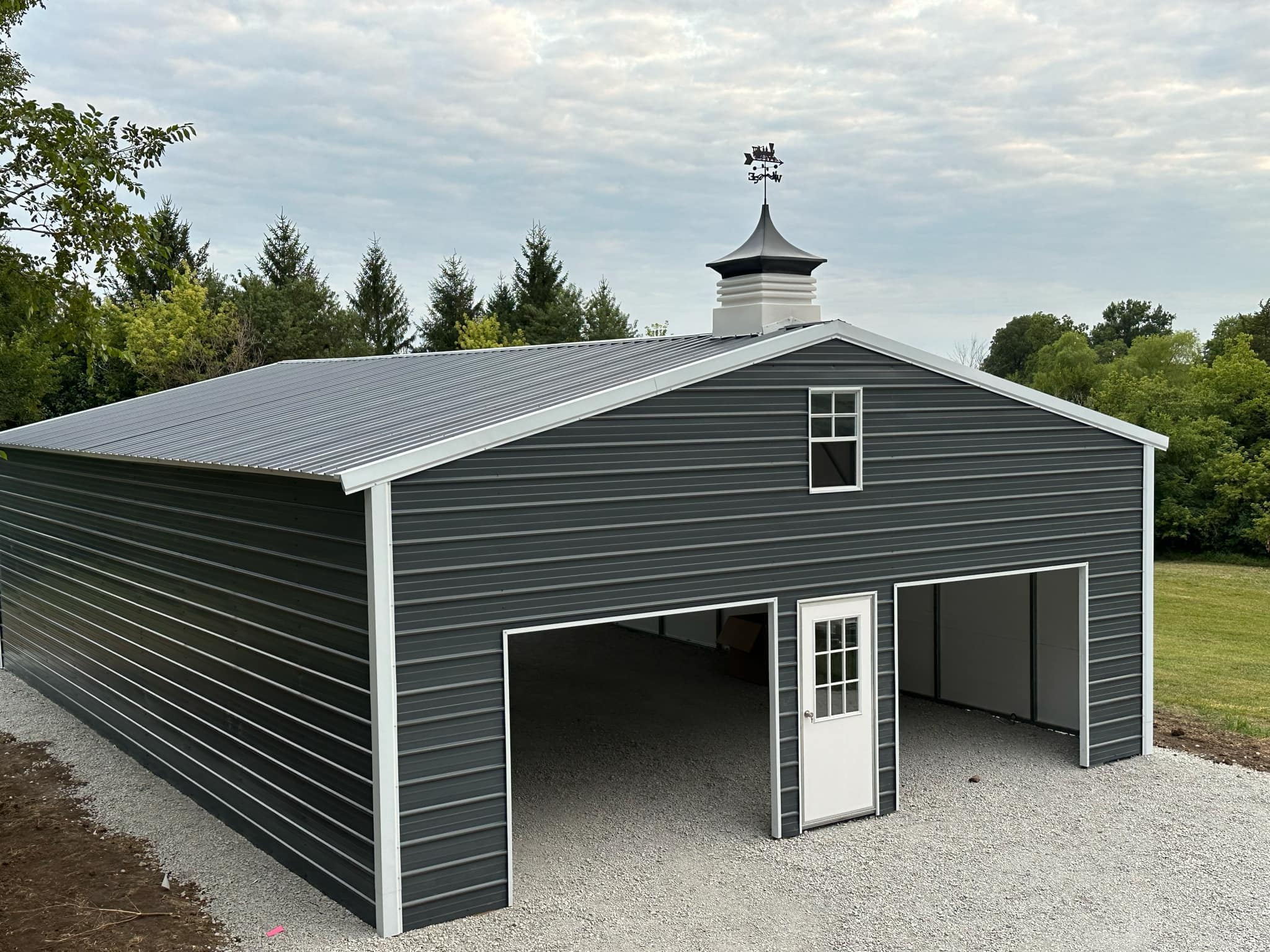 Exterior of a large charcoal colored building with two garage doors.