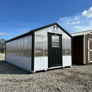 Exterior of mid-sized greenhouse, featuring polycarbonate walls and roof, with white and black accents on the building