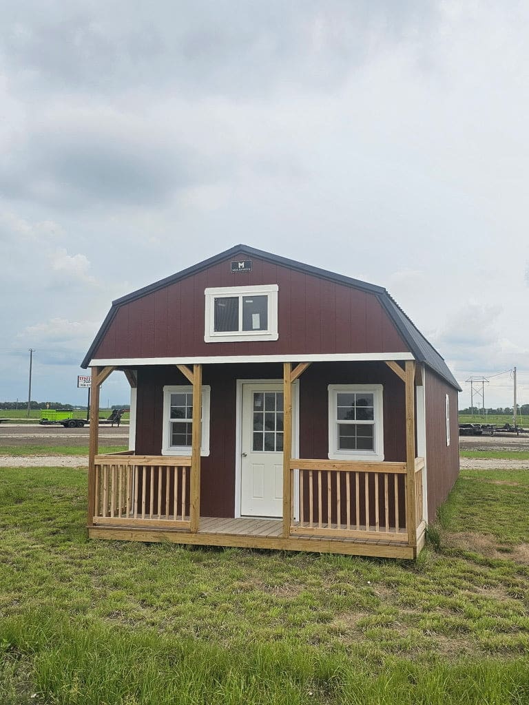 Exterior of a large, metal-sided cabin featuring a wood front porch, and a loft with a window