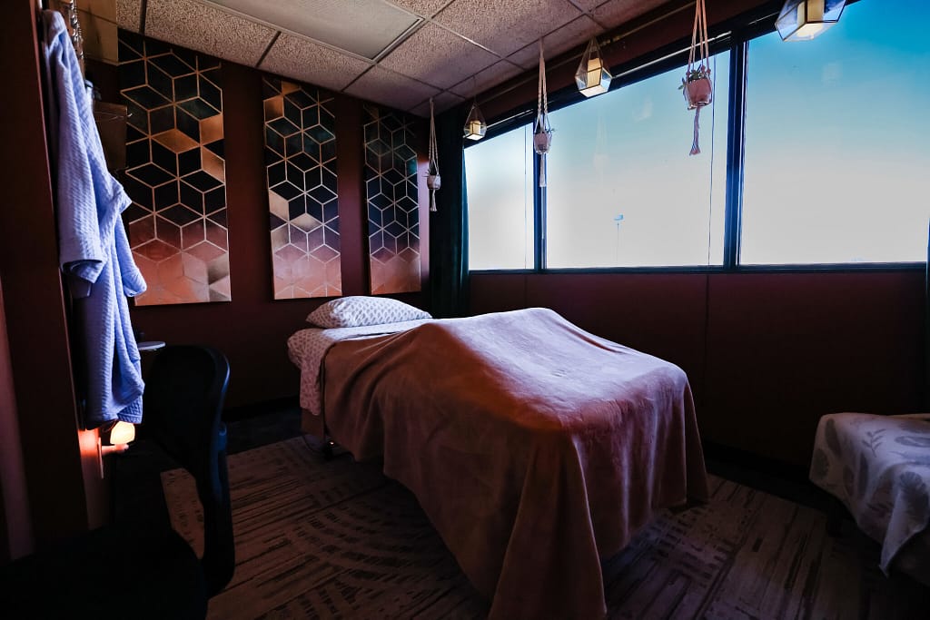 A massage table in Eva's office with open windows in the back.